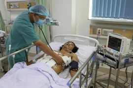 Bác sỹ theo dõi tình trạng bệnh nhân Hồ Ngọc Nguyễn. (Ảnh: Huỳnh Phúc Hậu/TTXVN)