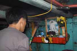 Ngư dân thực hiện nghi thức "cúng thuyền" cuối năm trong khoang lái của phương tiện. (Ảnh: Xuân Tiến/TTXVN)
