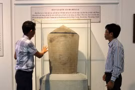 Cán bộ Bảo tàng tỉnh Ninh Thuận giới thiệu Bảo vật Quốc gia bia Hòa Lai. (Ảnh: Nguyễn Thành/TTXVN)