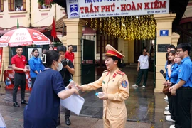 Cán bộ, chiến sỹ phòng Cảnh sát Giao thông, Công an thành phố Hà Nội phát nước, động viên các sỹ tử tại điểm thi trường THPT Trần Phú-Hoàn Kiếm. (Ảnh: Phạm Kiên/ TTXVN)