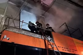 Lực lượng phòng cháy chữa cháy và cứu hộ cứu nạn dùng thang đưa người từ tầng 3 xuống. (Ảnh: TTXVN phát)