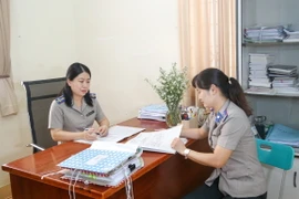 Bà Hồ Chí Bửu Nghi, Chi Cục trưởng, Chi Cục thi hành án dân sự Thị xã Hòa Thành, tỉnh Tây Ninh (bên trái) trao đổi xử lý vụ việc thi hành án khó cùng chấp hành viên. (Ảnh: Giang Phương/TTXVN) 