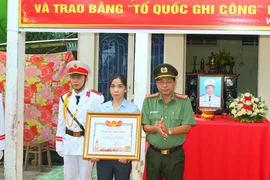 Đại tá Nguyễn Văn Hiểu trao Bằng Tổ quốc ghi công cho vợ Liệt sỹ Hồ Tấn Dương. (Ảnh: TTXVN phát)