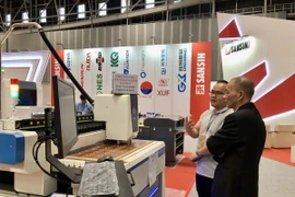 Khách tham quan tìm hiểu về máy móc tự động hóa tại triển lãm. (Ảnh: Mỹ Phương/ TTXVN)