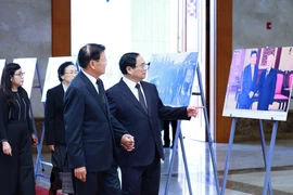 Thủ tướng Phạm Minh Chính giới thiệu với Tổng Bí thư, Chủ tịch nước Lào Thongloun Sisoulith một số hình ảnh về hoạt động đối ngoại của Tổng Bí thư Nguyễn Phú Trọng. (Ảnh: Dương Giang/TTXVN)