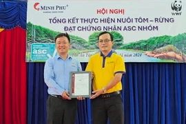 Ông Trần Phương Đại, Giám đốc kinh doanh Bureau Veritas Vietnam (BV) trao Chứng nhận ASC nhóm cho ông Lâm Thái Xuyên (phải), Giám đốc Công ty trách nhiệm hữu hạn Xã hội tôm chứng nhận Minh Phú. (Ảnh: Kim Há/TTXVN)