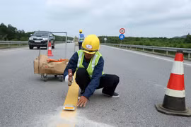 Thi công bổ sung lắp đặt các đinh phản quang giữa tim đường có hai làn xe. (Ảnh: Đỗ Trưởng/TTXVN)