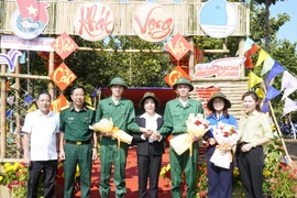 Hai anh em Nguyễn Tiến Thành và Nguyễn Tiến Đạt chụp ảnh lưu niệm cùng lãnh đạo huyện Phú Riềng và Ban Chỉ huy Quân sự huyện. (Ảnh: TTXVN phát)