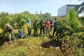 Công an tỉnh An Giang đưa đối tượng Thuận đi thu hồi tang vật vụ án. (Ảnh: TTXVN phát)