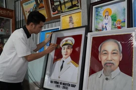 Anh Nguyễn Minh Trí hoàn thiện bức tranh gói vải chân dung Đại tướng Võ Nguyên Giáp. (Ảnh: Văn Sĩ/TTXVN)