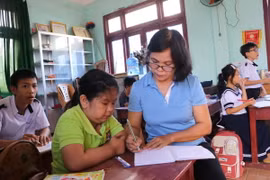 Cô giáo Nguyễn Thị Hương, xã Hành Minh, huyện Nghĩa Hành, hướng dẫn học sinh viết bài.( Ảnh: Đinh Hương/ TTXVN)