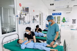 Bác sỹ Trần Minh Long kiểm tra sức khỏe bệnh nhi sau ca phẫu thuật. (Ảnh: Bích Huệ/ TTXVN)