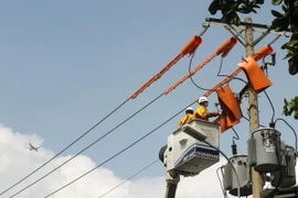 Công nhân ngành điện Thành phố Hồ Chí Minh nỗ lực duy trì mạch điện trong những ngày nắng gắt, hơi nóng của bêtông phả ra từ mặt đường, làm nhiệt độ lên tới 51-52 độ C. (Ảnh: Thanh Vũ/TTXVN)