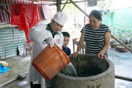 Quân y Bộ đội Biên phòng tỉnh Quảng Bình hỗ trợ người dân vùng lũ huyện Lệ Thủy khử khuẩn nguồn nước sinh hoạt. (Ảnh: TTXVN phát)