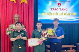 Phó Bí thư Thường trực Tỉnh đoàn, Phó Chủ tịch Hội Liên hiệp thanh niên Việt Nam tỉnh Cao Bằng Hà Ngọc Huy trao tặng Huy hiệu “Tuổi trẻ dũng cảm” cho Binh nhất Lý Văn Vũ. (Ảnh: TTXVN phát)