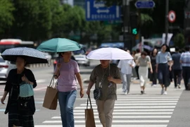 Người dân di chuyển trên đường phố dưới trời nắng nóng tại Seoul, Hàn Quốc, ngày 17/6/2024. (Ảnh: Yonhap/TTXVN)