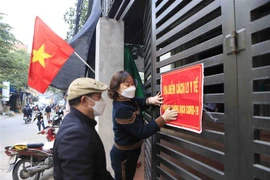 Các thành viên ổ COVID cộng đồng Mậu Lâm, phường Khai Quang thành phố Vĩnh Yên dán thông báo cách ly tại gia đình có người mắc COVID-19. (Ảnh: Hoàng Hùng/TTXVN)