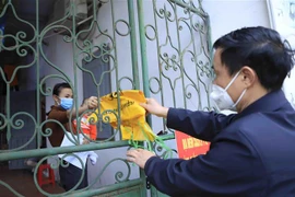 Một gia đình có thành viên mắc F0 nhận túi đựng chất thải y tế từ thành viên tổ COVID cộng đồng. (Ảnh minh họa: Hoàng Hùng/TTXVN)