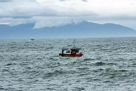 Lực lượng biên phòng đang tìm kiếm người mất tích trong vụ chìm canô du lịch tại Cửa Đại. (Ảnh: TTXVN)