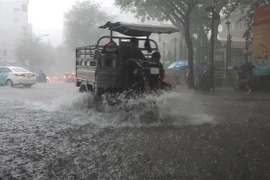 Các phương tiện lưu thông trên đường Nguyễn Bỉnh Khiêm, quận 1 ngập nước. (Ảnh: Xuân Dự/TTXVN)