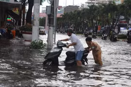 Cảnh sát giao thông thành phố Bạc Liêu giúp dân đưa xe chết máy qua vùng ngập nước. (Ảnh: Huỳnh Sử/TTXVN)