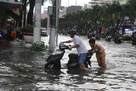 Cảnh sát giao thông thành phố Bạc Liêu giúp dân đưa xe chết máy qua vùng ngập nước. (Ảnh: Huỳnh Sử/TTXVN)