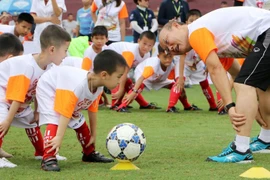 HLV Park Hang Seo hướng dẫn các em học sinh khởi động trước khi chơi bóng đá. (Ảnh: Trung Kiên/TTXVN)