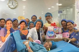 Ban giám đốc, êkíp trực đêm tại Bệnh viện Từ Dũ tặng quà cho sản phụ sinh con đầu tiên trong năm 2020. (Ảnh: Đinh Hằng/TTXVN)
