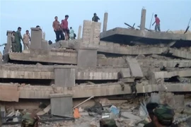 Lực lượng cứu hộ tìm kiếm nạn nhân dưới đống đổ nát của công trình đang thi công bị đổ sập. (Ảnh: AFP/TTXVN)