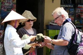 Du khách nước ngoài mua một món đồ lưu niệm tại phố cổ Hà Nội. (Ảnh: Trần Việt/TTXVN)