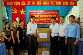 Ông Đỗ Cường, Phó Tổng Biên tập Báo Điện tử VietnamPlus, Chủ tịch Hội Cựu chiến binh - TTXVN trao tặng quà cho trường Tiểu học B Minh Tân. (Ảnh: Minh Tâm/Vietnam+)