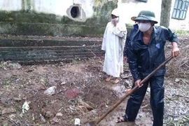 Người dân đào một khu vực chôn các thùng thuốc trừ sâu đã hết hạn. (Ảnh: Trịnh Duy Hưng/TTXVN)