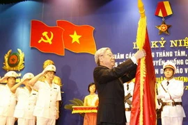 Chủ tịch Quốc hội Nguyễn Phú Trọng gắn Huân chương Sao Vàng lên lá cờ truyền thống của Công an thành phố Hà Nội. (Ảnh : Trí Dũng/TTXVN)
