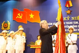 Chủ tịch Quốc hội Nguyễn Phú Trọng gắn Huân chương Sao Vàng lên lá cờ truyền thống của Công an thành phố Hà Nội. (Ảnh : Trí Dũng/TTXVN)