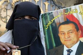 Một người ủng hộ cựu Tổng thống Hosni Mubarak cầm ảnh của ông bên ngoài bệnh viện nơi ông điều trị ở Cairo. (Nguồn: AFP/TTXVN)
