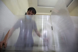 Ông Sơn đang tiến hành lắp đặt hệ thống chắn giọt bắn tự chế. (Ảnh: PV/Vietnam+) 