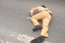 Cú đâm mạnh khiến Trung úy cảnh sát bị thương, nằm bất động trên đường. (Ảnh: PV/Vietnam+)