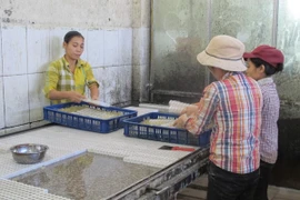 Nhân viên với tay trần, chân đi đất ​đang thoăn thoắt bóc nhân kẹo dẻo (Ảnh: Đức Duy/Vietnam+)