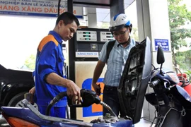 Nhân viên Petrolimex đang bơm xăng cho khách hàng (Ảnh: TTXVN)