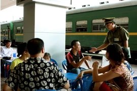 Cán bộ Ga Hà Nội nhắc nhở hành khách hút thuốc đúng nơi quy định. (Ảnh: Dương Ngọc/TTXVN)