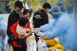 Các bác sỹ thực hiện sát khuẩn tay cho một cháu bé trong đoàn công dân cách ly tập trung theo dõi COVID-19. (Ảnh: TTXVN)