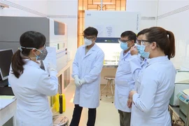 Các xét nghiệm viên tại Trung tâm Kiểm soát bệnh tật Đồng Nai tìm hiểu quy trình hoạt động của hệ thống máy xét nghiệm Real Time-PCR. (Ảnh: Lê Xuân/TTXVN)