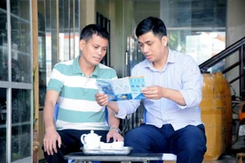 Cán bộ bảo hiểm xã hội tuyên truyền chính sách Bảo hiểm xã hội tự nguyện cho người dân. (Ảnh: Quang Quyết/TTXVN)