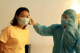 Đo thân nhiệt lao động nước ngoài tại một khách sạn. (Ảnh minh họa. Hoàng Hùng/TTXVN)