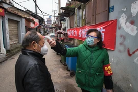 Kiểm tra thân nhiệt của người dân nhằm ngăn chặn sự lây lan của COVID-19 tại Vũ Hán, tỉnh Hồ Bắc, Trung Quốc. (Ảnh: THX/TTXVN)