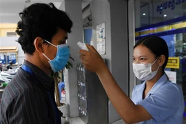Kiểm tra thân nhiệt người dân trước cửa một ngân hàng nhằm phòng dịch COVID-19 lây lan, tại Phnom Penh, Campuchia. (Ảnh: AFP/TTXVN)