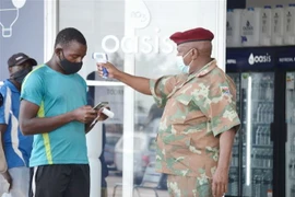 Binh lính Nam Phi tiến hành đo kiểm tra thân nhiệt cho người dân. (Ảnh: TTXVN)