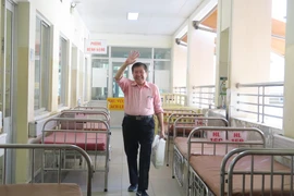 Bệnh nhân T.K.H (73 tuổi, quốc tịch Mỹ) tươi cười bước ra từ khu vực cách ly chiều 21/2/2020. (Ảnh: Đinh Hằng/TTXVN)