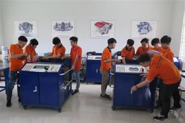 Sinh viên Khoa cơ, điện, điện tử nghiên cứu mô hình động cơ xe ôtô hiện đại. (Ảnh: Minh Hưng/TTXVN)