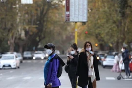 Người dân đeo khẩu trang đợi xe buýt ở Rome, Italy. (Ảnh: THX/TTXVN)
